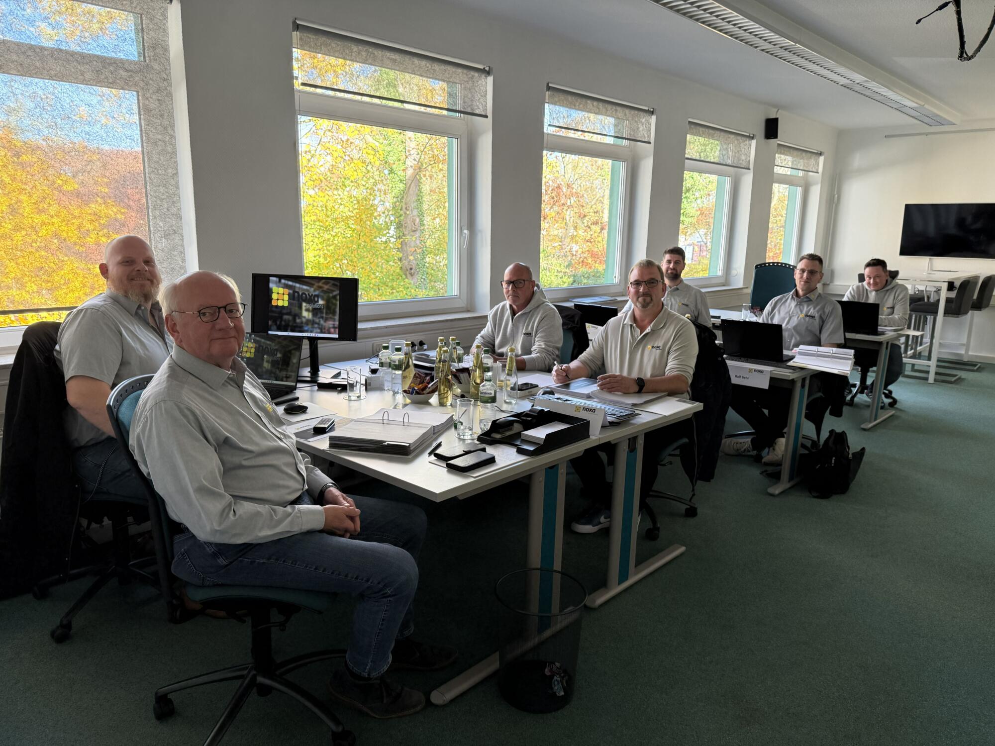 Das Bild zeigt die neuen Mitarbeiter von November am Schreibtisch sitzen